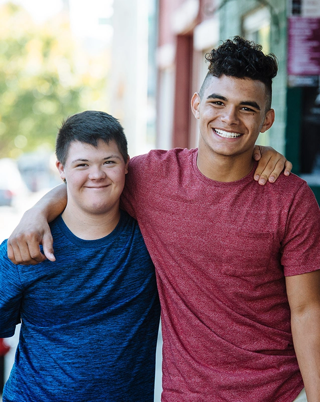 Two male best buddies participants walking with arms over shoulders